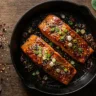 hot honey salmon recipe with caramelized glaze sesame seeds and lemon in cast iron skillet
