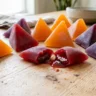 Colorful triangular fruit snacks with one bitten open showing the liquid center