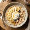 A bowl of creamy high protein oatmeal topped with Greek yogurt and banana