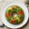 A molded savory aspic with vegetables and herbs suspended in clear gelatin