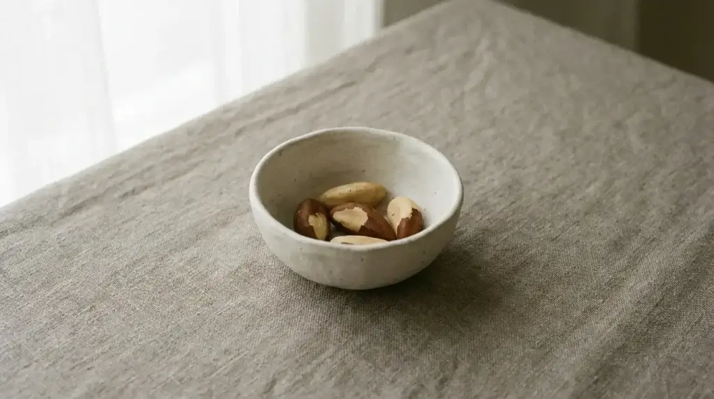 A small bowl containing a few Brazil nuts
