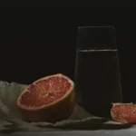 Grapefruit cut in half beside a glass of water