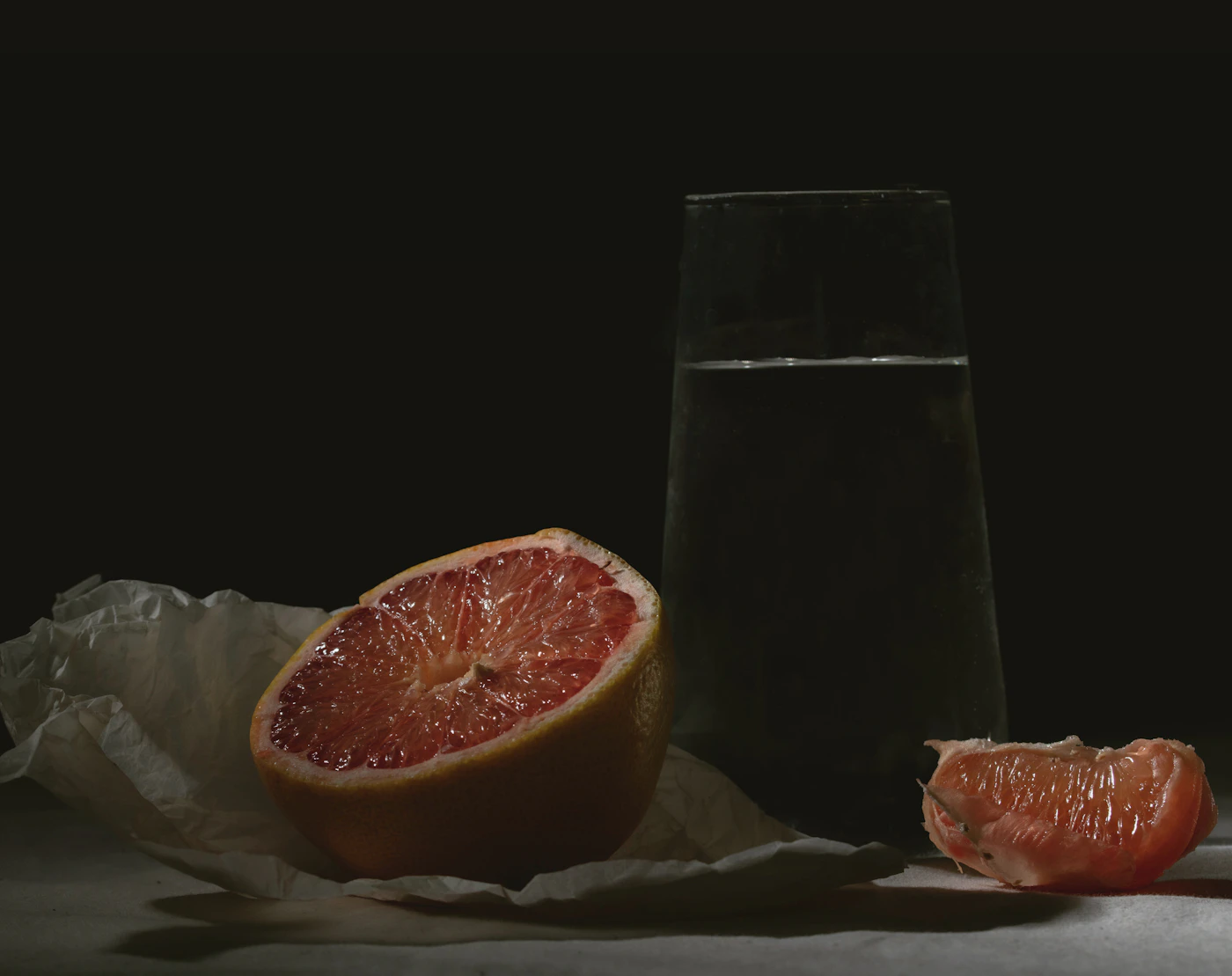 Grapefruit cut in half beside a glass of water