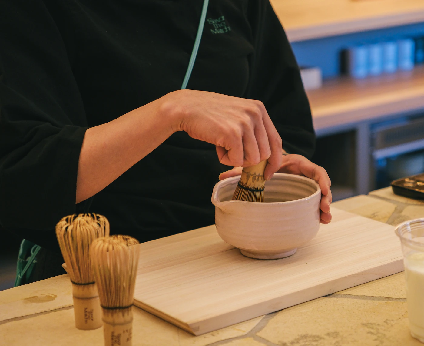 Matcha powder whisked in a ceramic bowl with a bamboo whisk