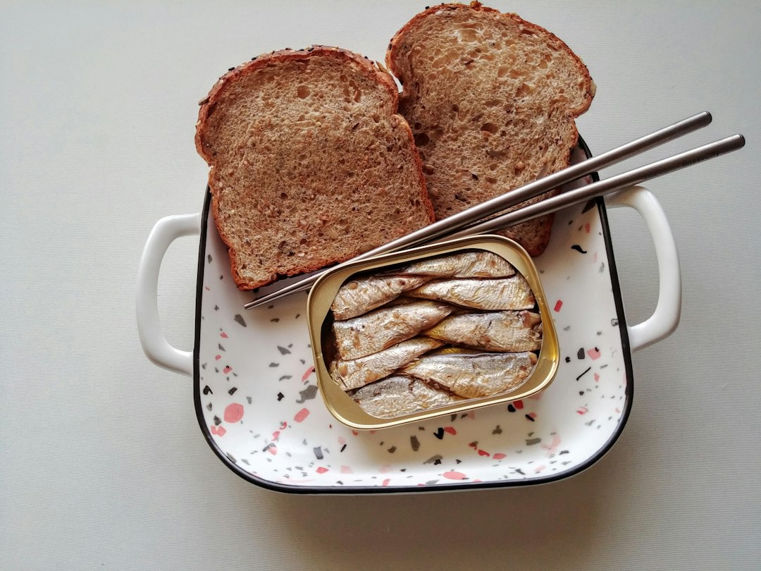 Open tin of sardines served with slices of whole grain bread