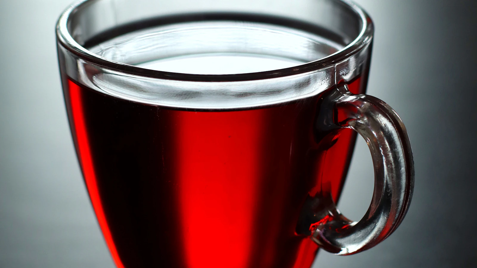 Deep red hibiscus tea in a glass cup on a table