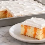 Orange jello poke cake square with orange streaks through vanilla crumb and white whipped topping